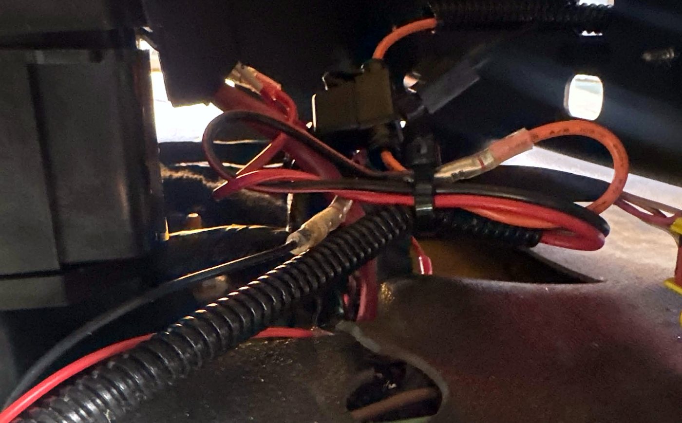 Loose power and ground wires with an unsecured inline fuse under a bus seat