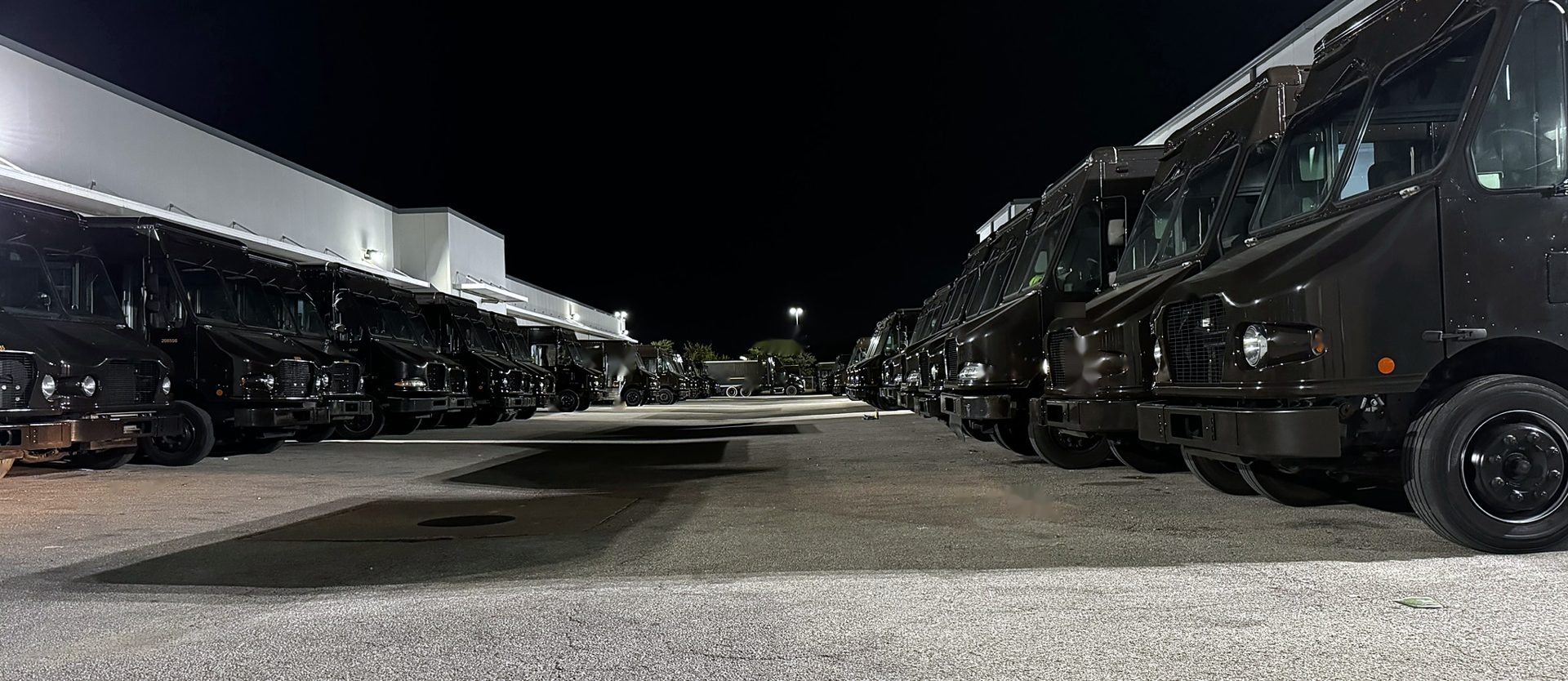 Rows of delivery vans lined up at a depot at night