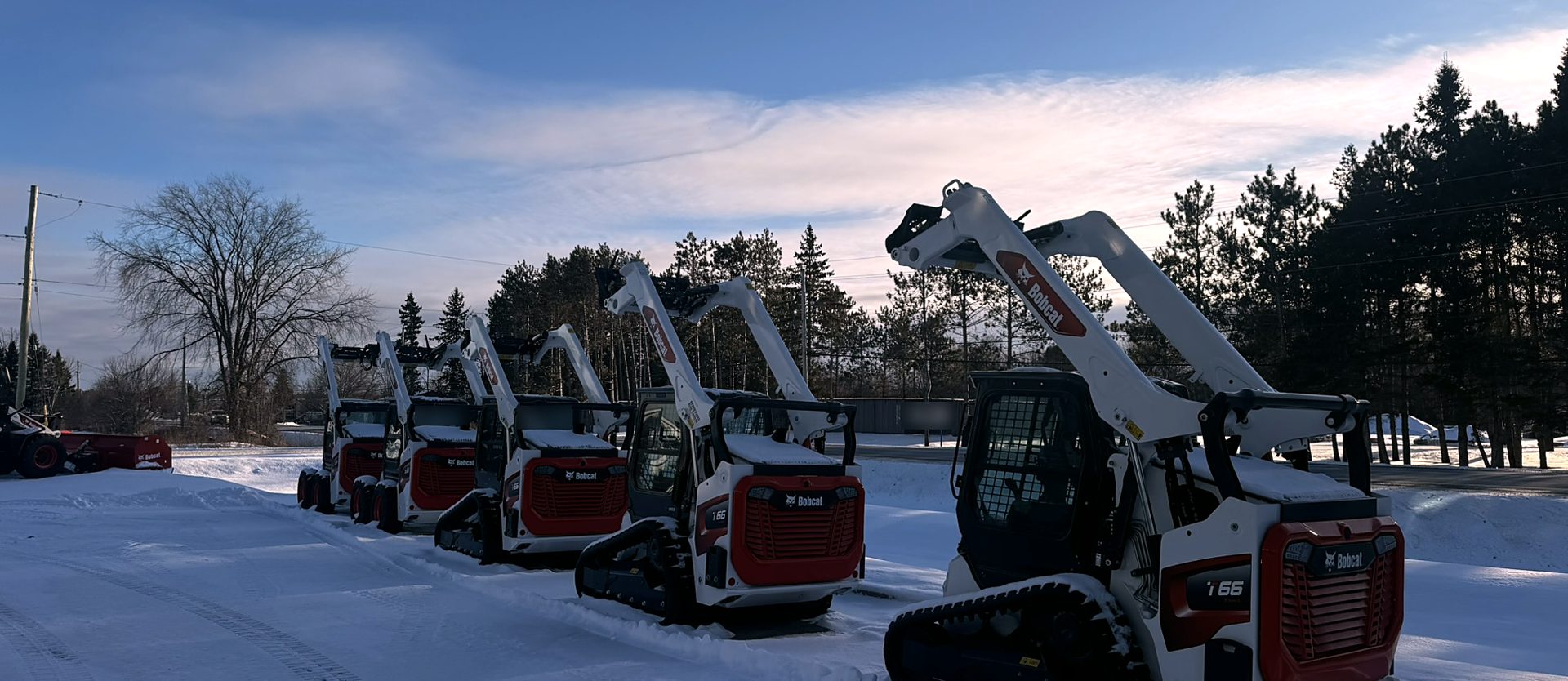 Row of compact track loaders in the snow