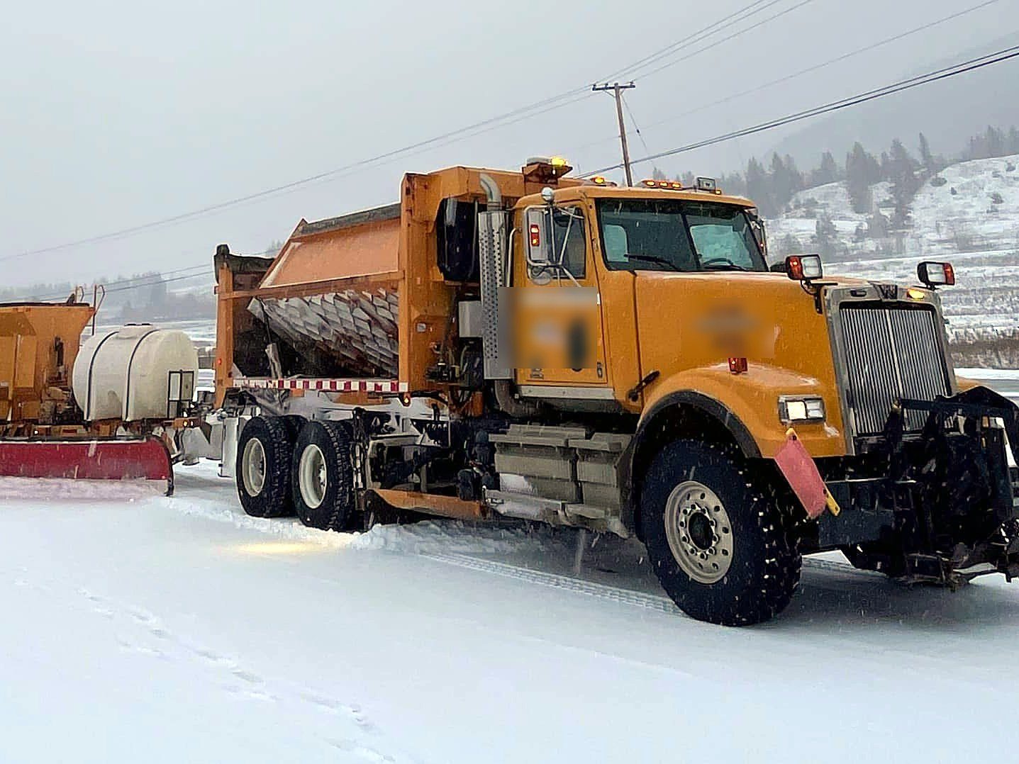 Plow truck with tow plow working in snow