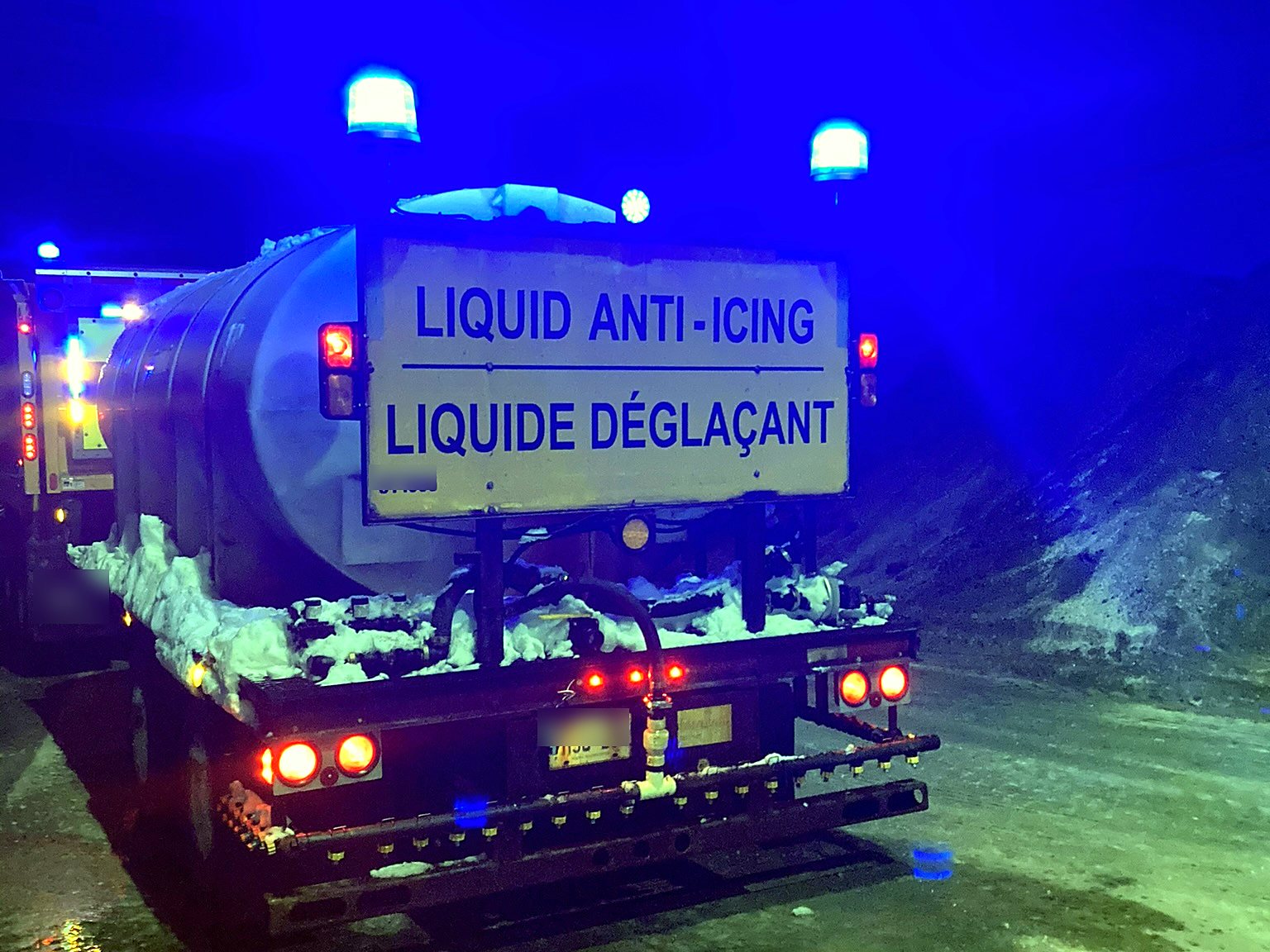 Brine trailer with blue strobe beacons lit at dusk