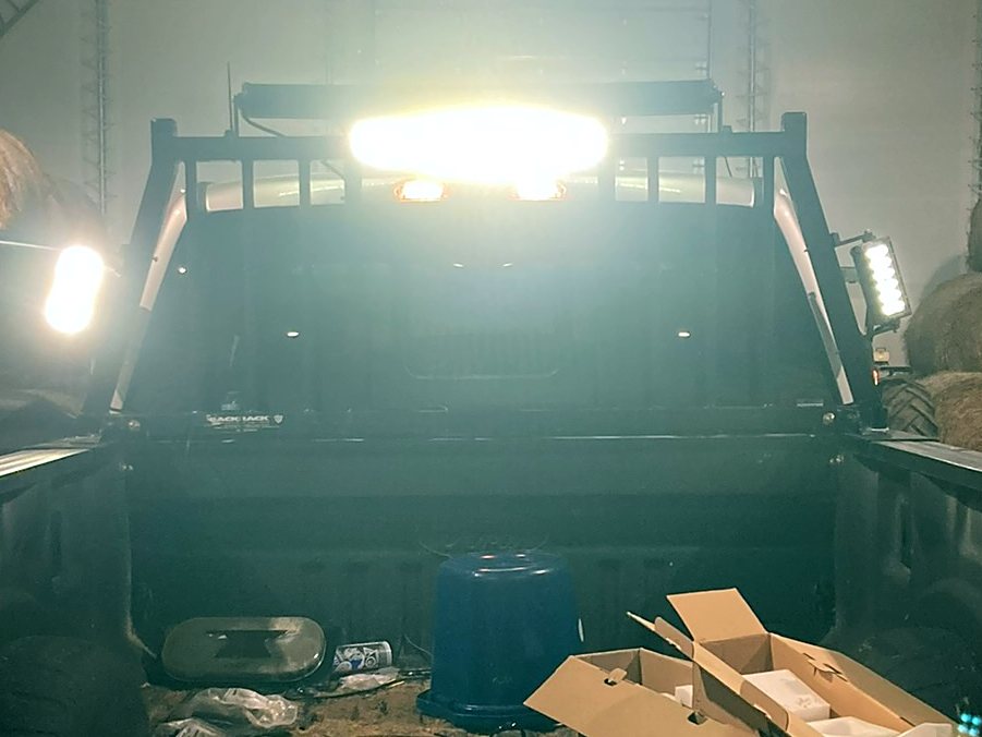 Headache rack light bar and side work lights lit inside a hay barn