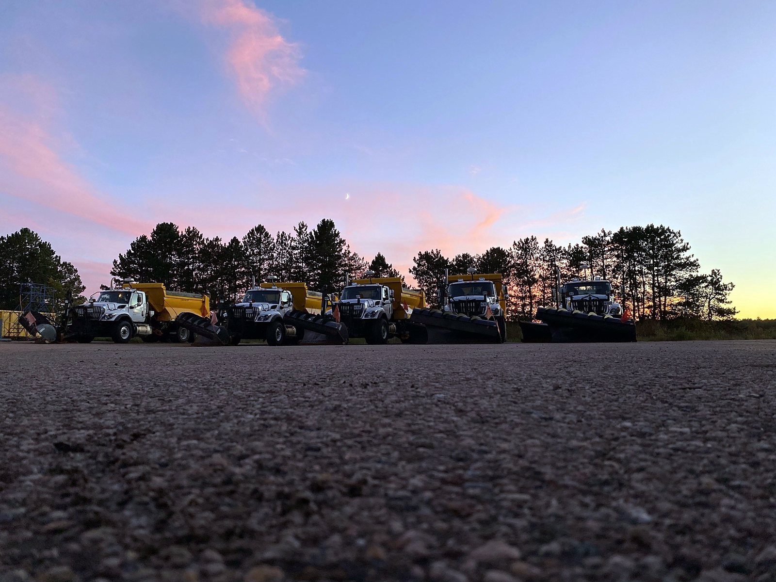 Plow trucks lined up at sunset