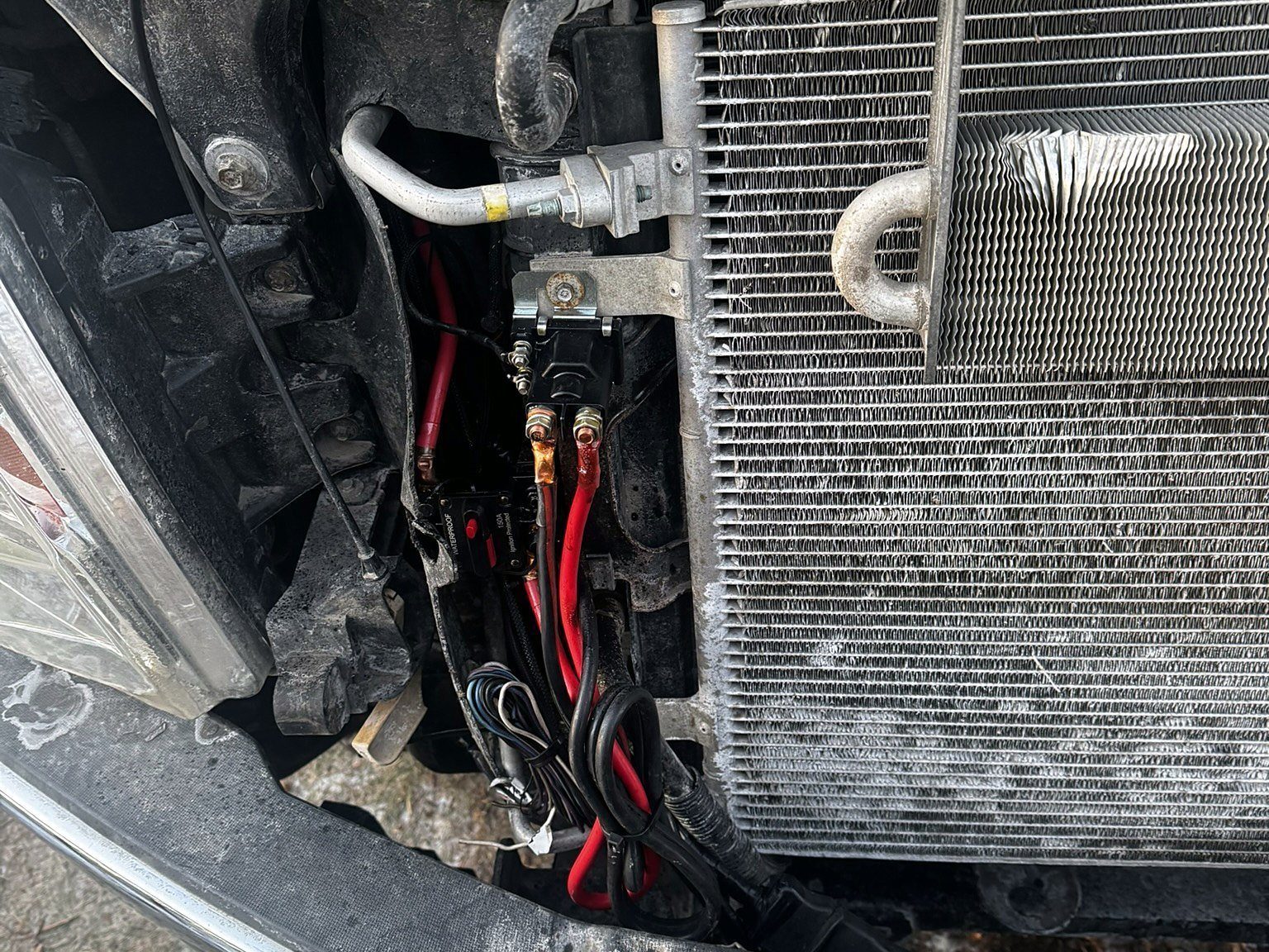 Lighting relay wiring mounted behind a pickup grille