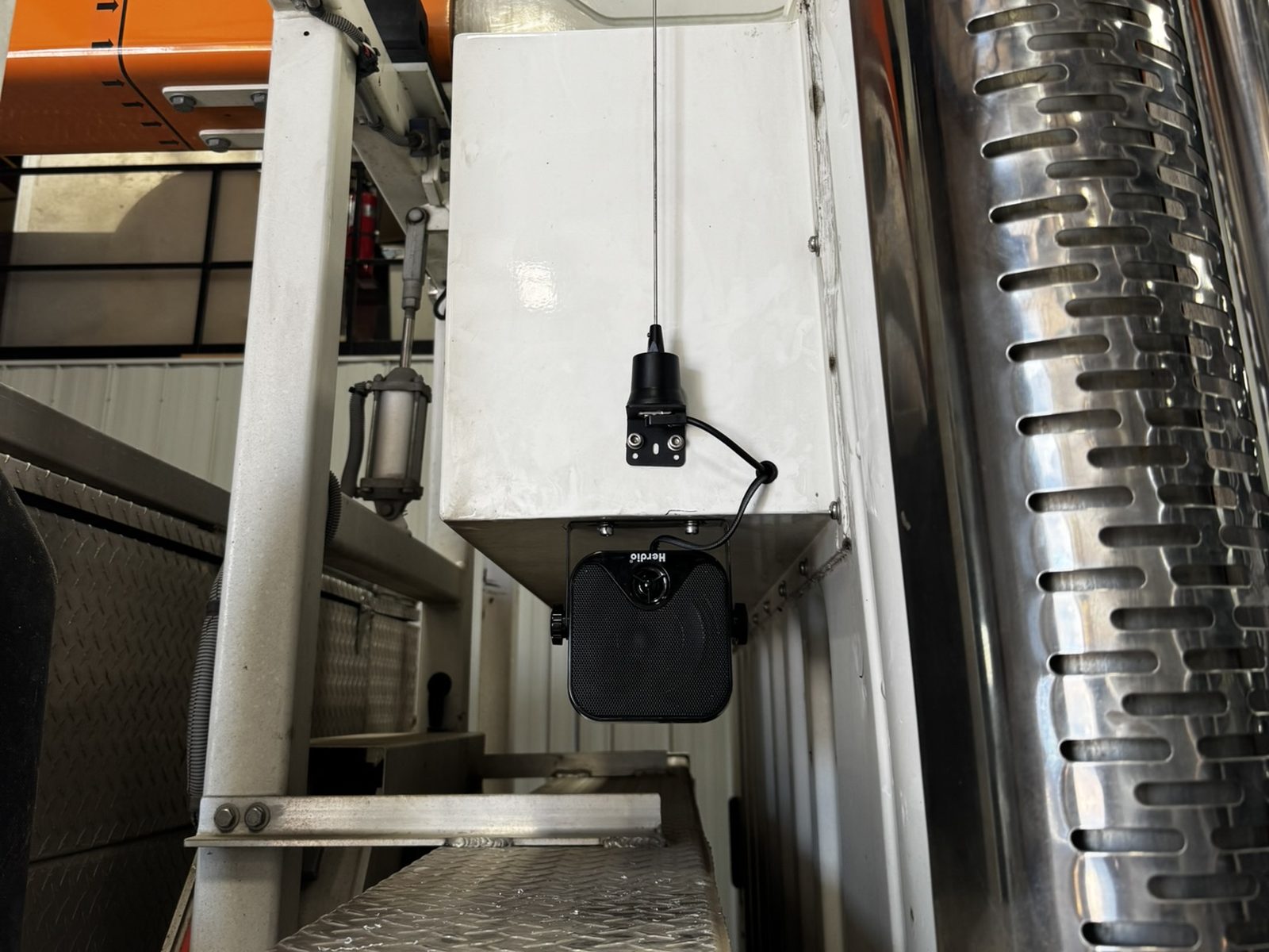 Radio antenna and outside speaker mounted on a bucket truck body
