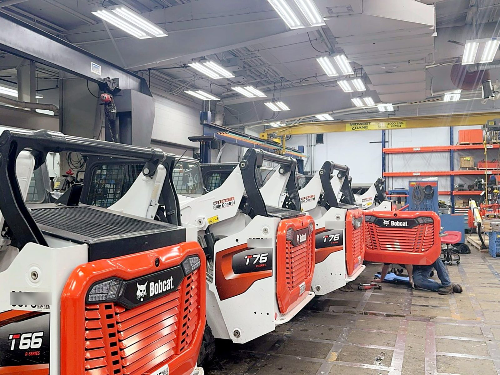 Compact track loaders lined up in a service shop