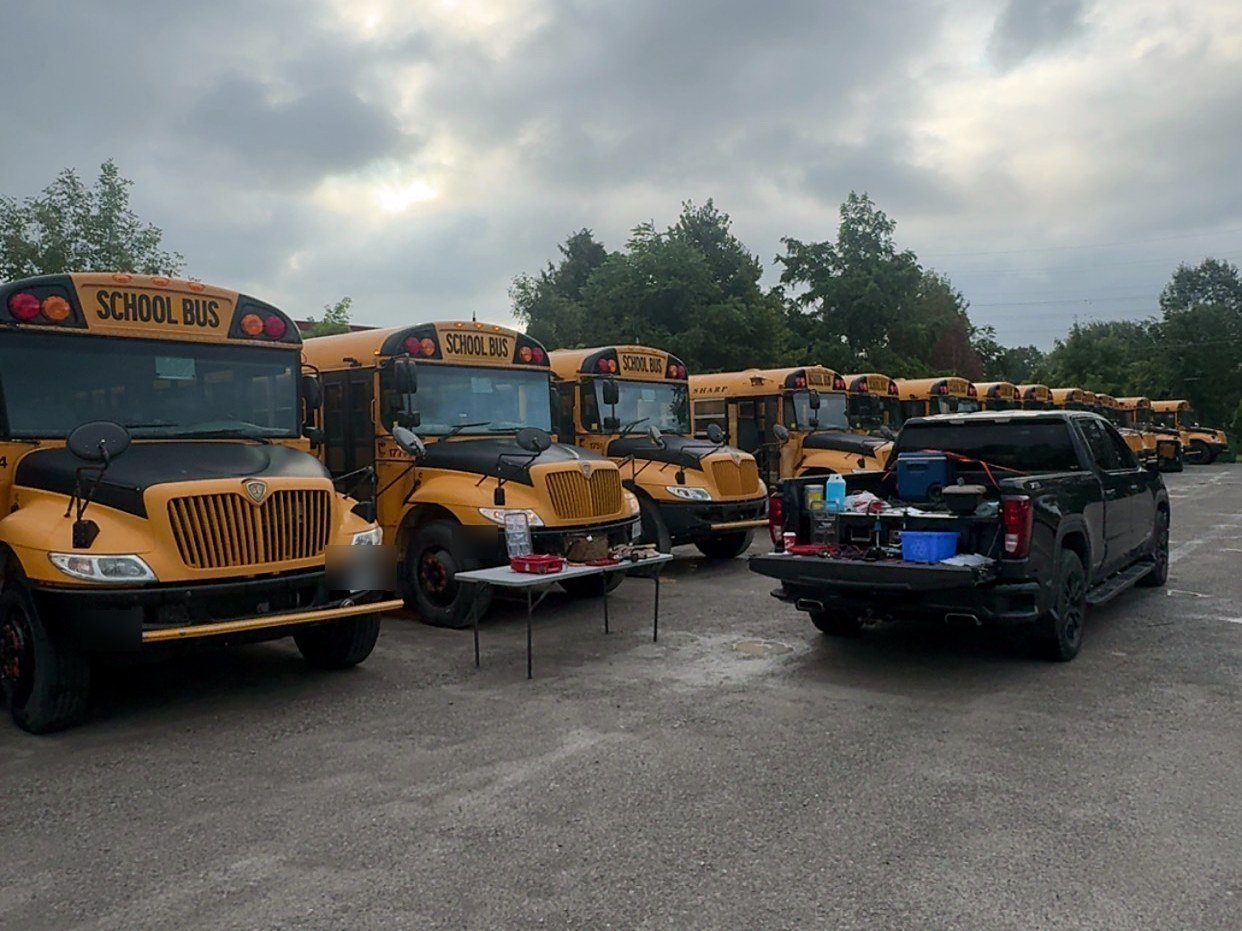 WTM pickup and work table beside a row of school buses